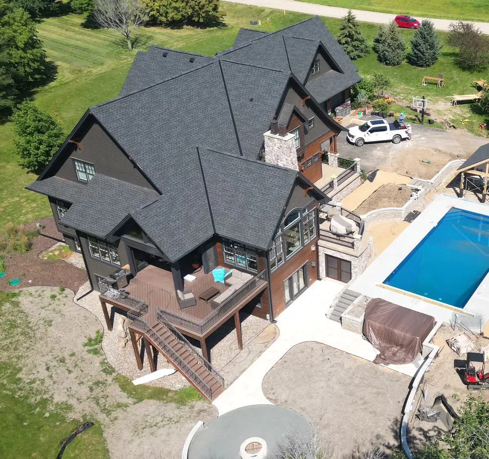 Aerial view of a renovated two-story home with a charcoal exterior, new roof and wraparound deck.